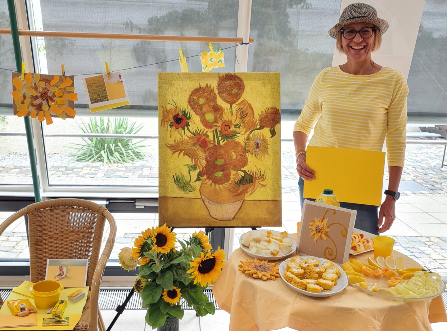 Petra Kellermann steht zwischen Gegenständen zur Farbe Gelb und einem Gemälde mit Sonnenblumen