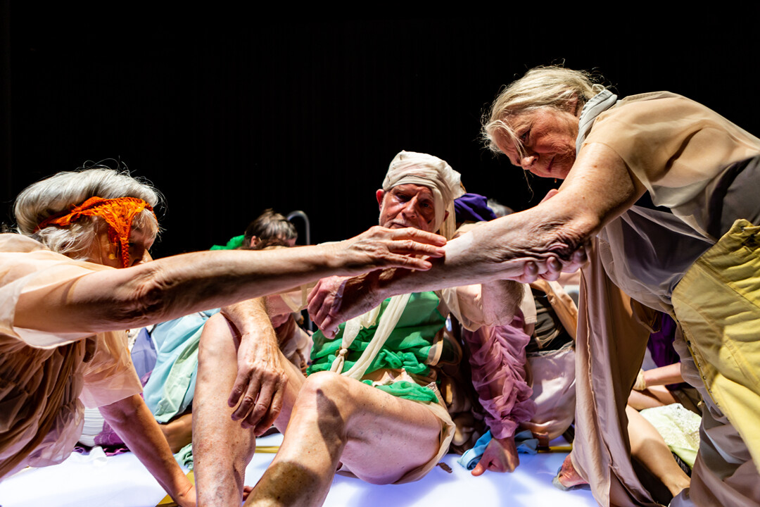 A group of elderly people on a stage, some of them wearing underwear and tights on their heads.