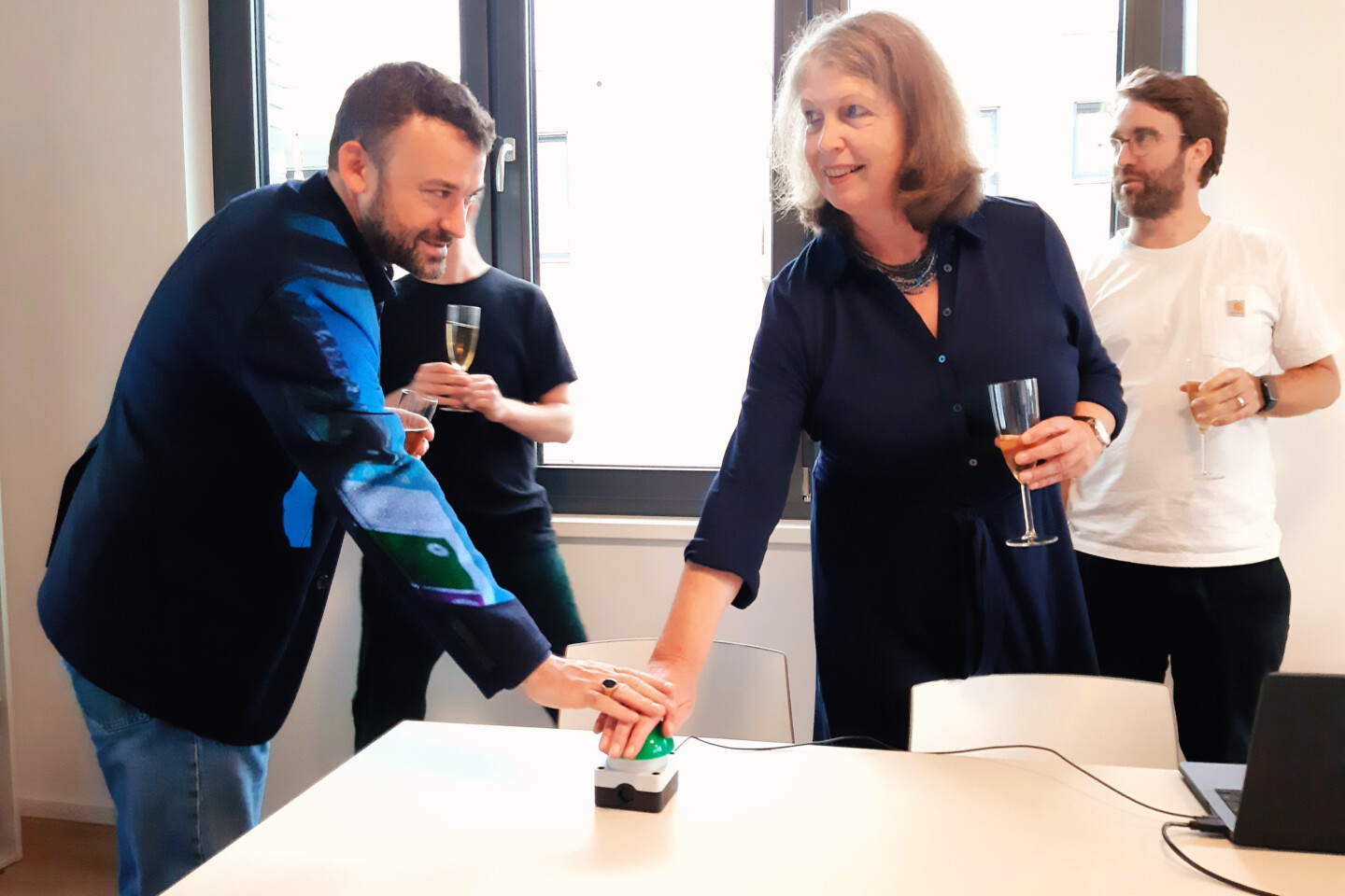 A man and a woman, ibk board member Benjamin Thele and kubia director Almuth Fricke, press a large green button together.