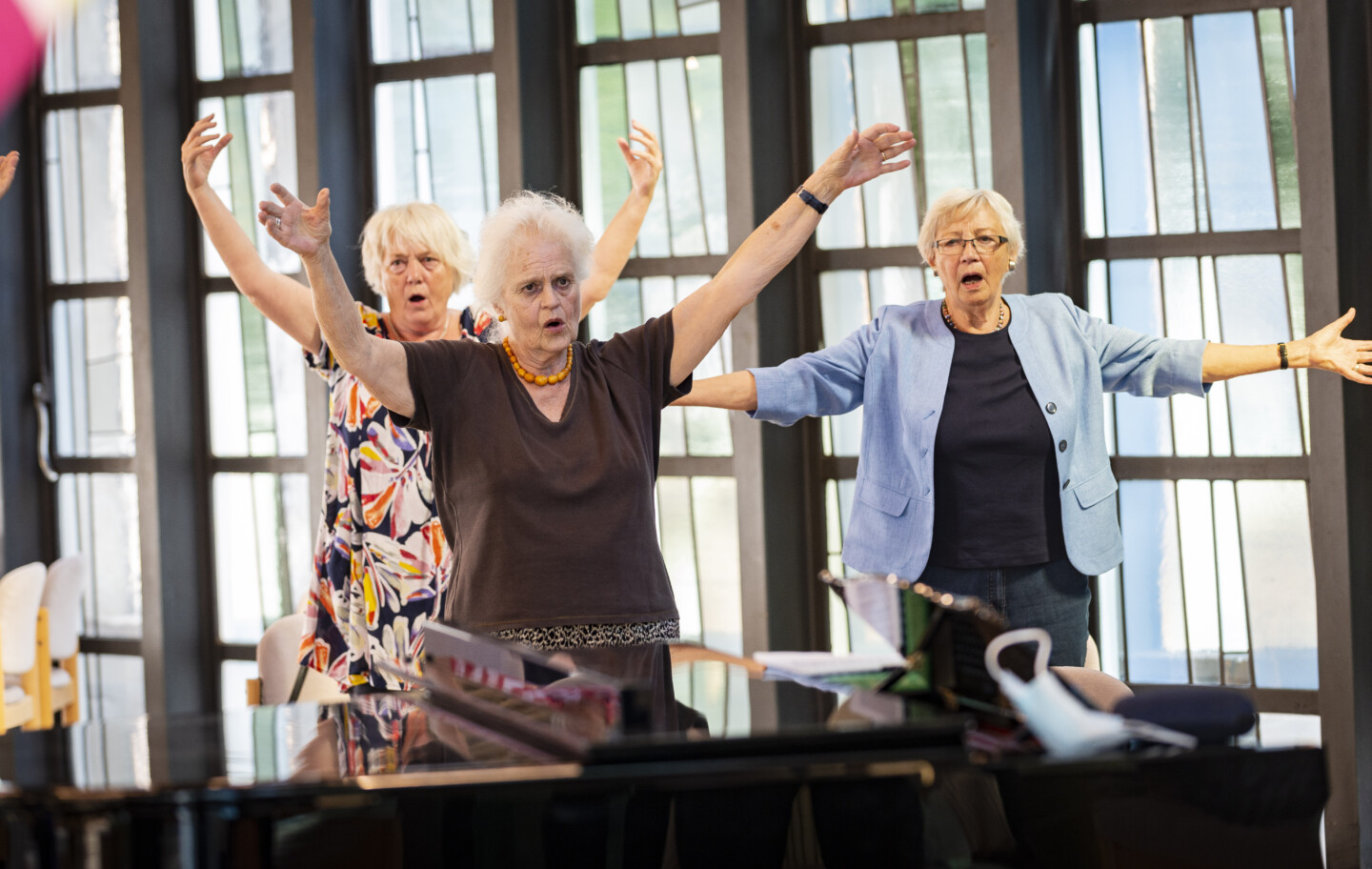Drei singende ältere Frauen mit erhobenen Armen