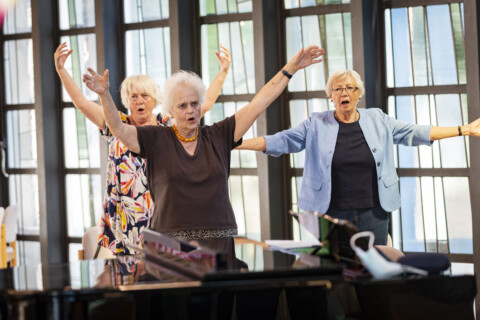 Drei singende ältere Frauen mit erhobenen Armen