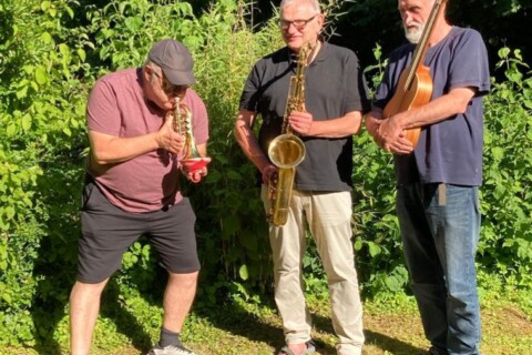 Drei Männern, die draußen Instrumente spielen.