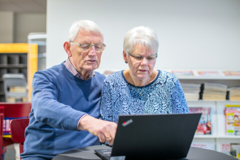 Ein Mann und eine Frau schauen auf einen Laptop