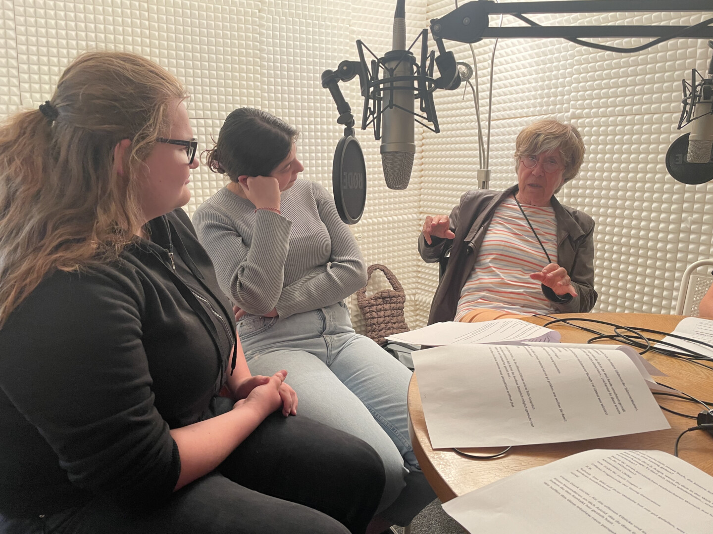 Zwei jüngere Frauen im Gespräch mit einer älteren Frau in einem Hörfunkstudio.