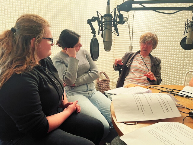 Zwei jüngere Frauen im Gespräch mit einer älteren Frau in einem Hörfunkstudio