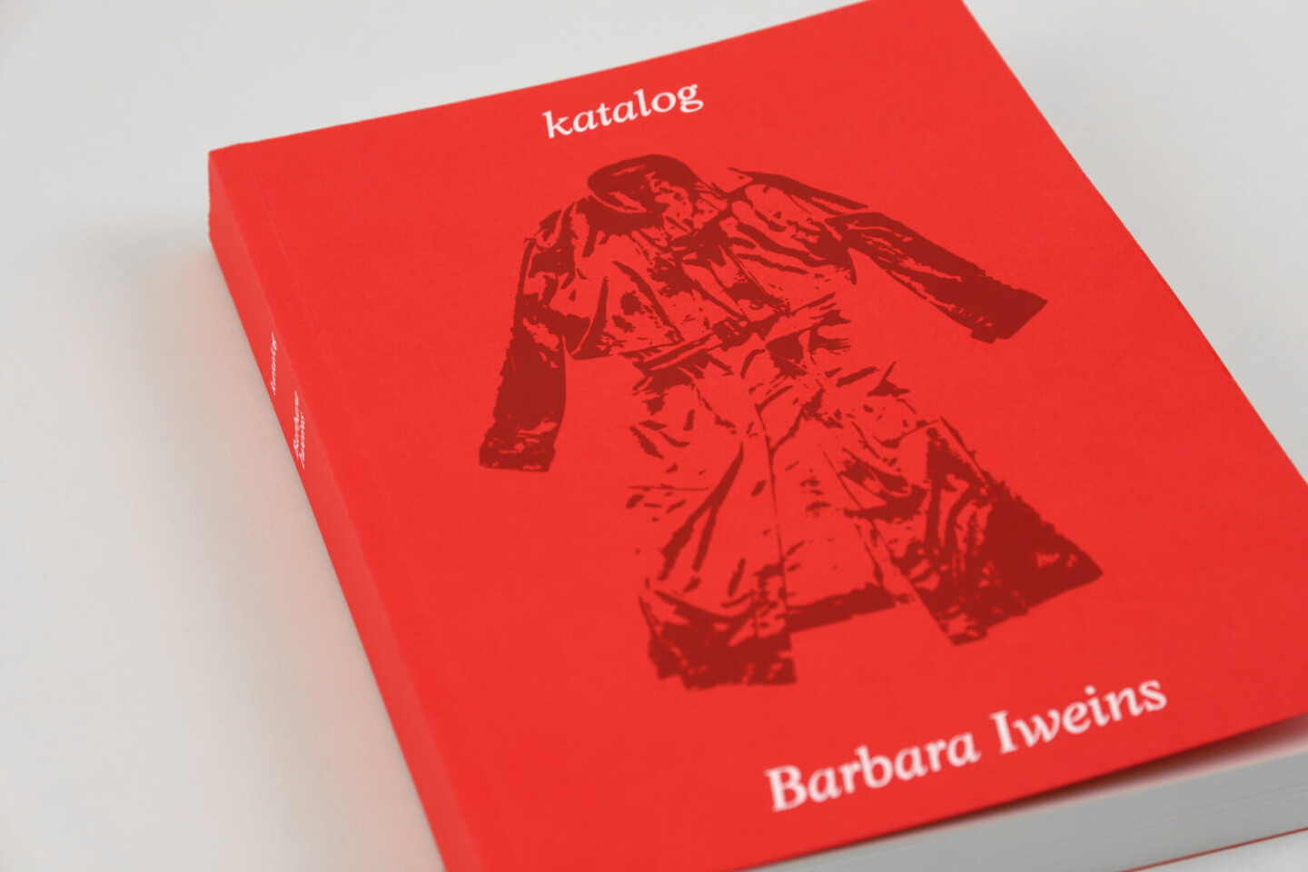 Das Bild zeigt das rot-orangefarbene Buch katalog von Barbara Iweins. Auf dem Cover ist ein rot gezeichneter Mantel abgebildet. Der Titel steht oben in Weiß, der Name der Autorin unten rechts.
