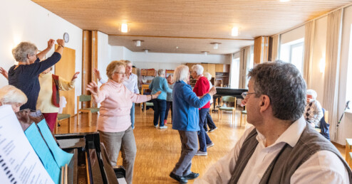 Ein Mann sitzt am Klavier und weitere Personen im Raum tanzen