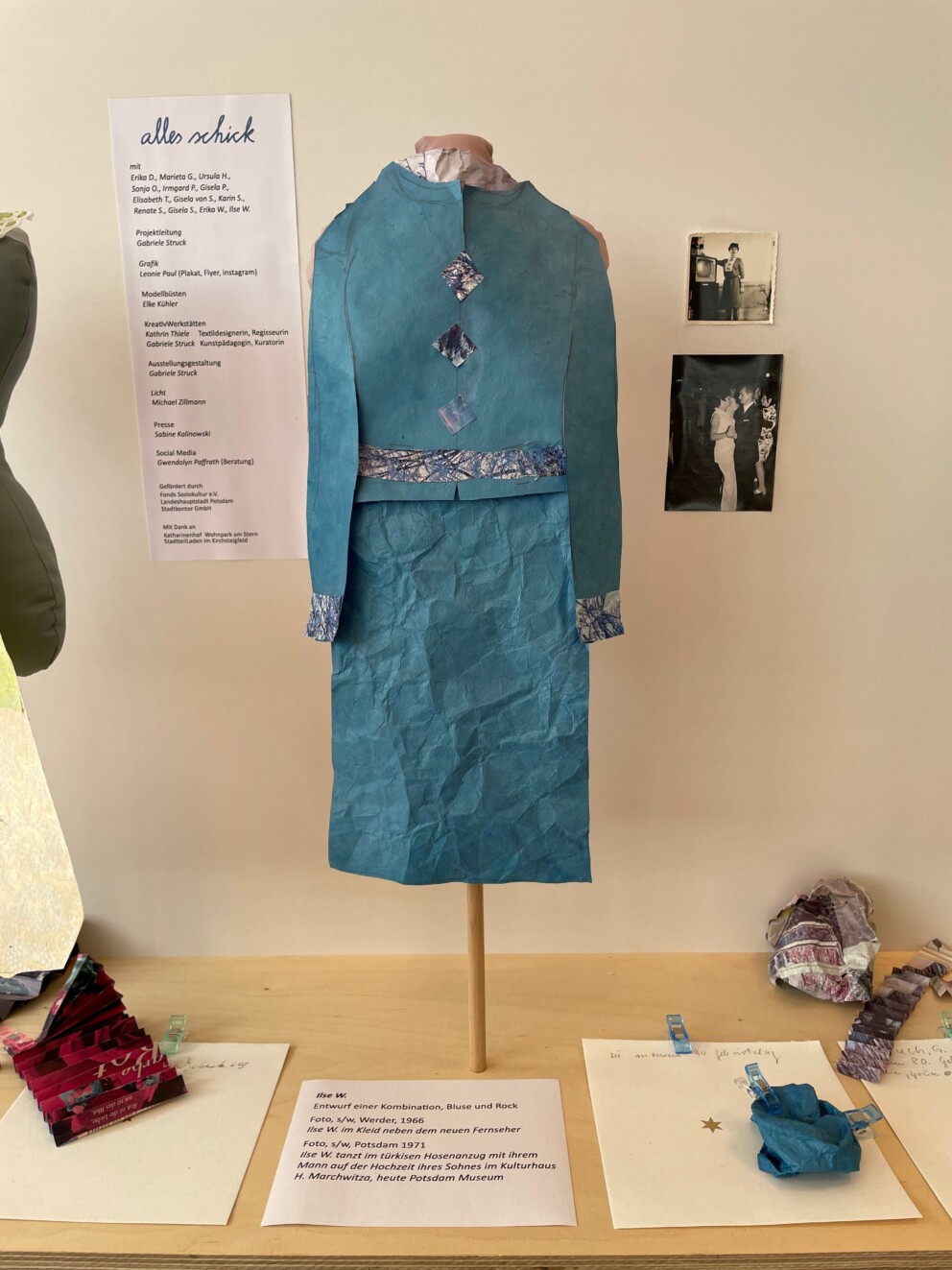 Ein ausgestelltes blaues Kleid aus Papier mit dauzgehörenden Beschreibungen des Kleids.