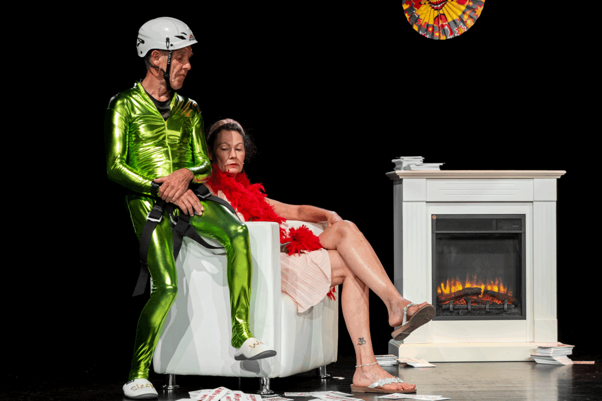 Ein Mann sitzt auf der Lehne eines Sessels. Im Sessel sitzt eine Frau.