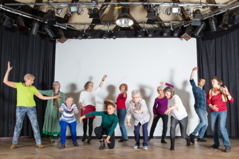 Es befinden sich mehrere Personen auf einer Bühne, die sich bewegen.
