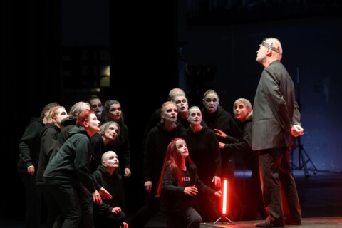 Ein Mann und eine Gruppe weiterer Personen stehen sich gegenüber.