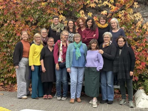 Gruppenfoto des 12. Weiterbildungskurses Kulturgeragogik vor Wand mit buntem Weinlaub. 14 Frauen und Kursbegleitung Clara Hense.