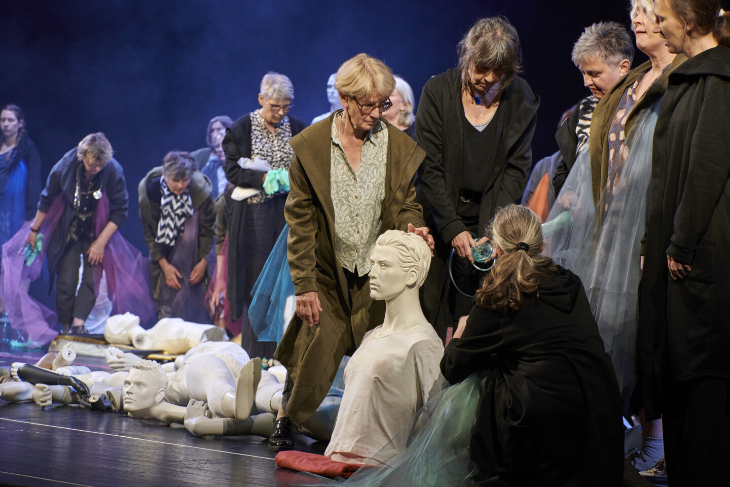 Fotografie: Mehrere Personen stehen um weiße, kopflose Puppen herum und betrachten sie.