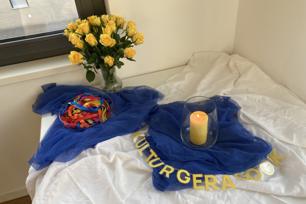 Tisch mit Strauß gelber Rosen, Kerze und Girlande "Kulturgeragogik"