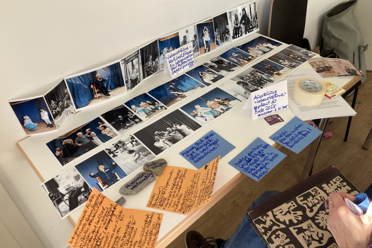 Auf einem Tisch liegen Fotos und Hinweiszettel, die das Pantomime-Projekt dokumentieren.