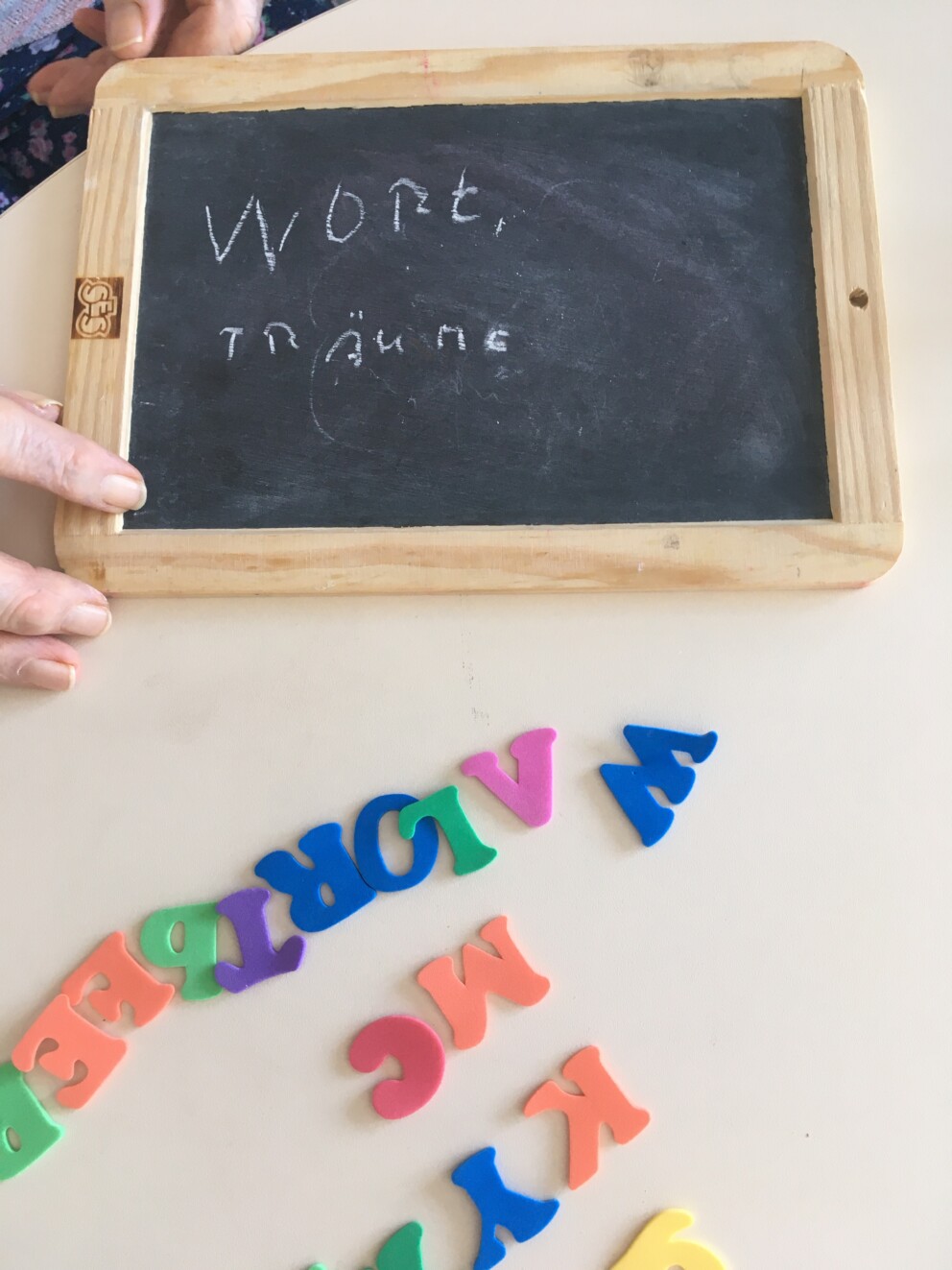 Auf einem Tisch liegen eine Schiefertafel und Magnetbuchstaben