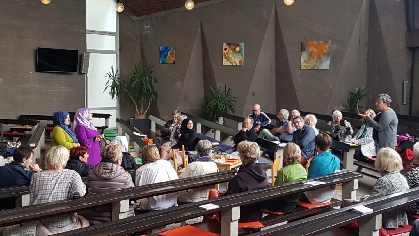 Eine Gruppe sitzt in Kirchenbänken in einer Gesprächs- oder Workshop-Situation.