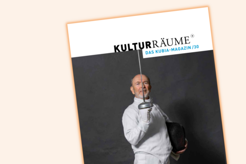 Die Grafik bildet das Cover des kubia-Magazin Kulturräume+ Nr. 30 im Anschnitt ab. Das Titelfoto zeigt einen älteren Mann im Fechtanzug in aufrechtstehender Haltung. Er blickt geradeaus und hält einen Degen so in der Hand, dass die Klinge sich senkrecht vor seiner Nase befindet.